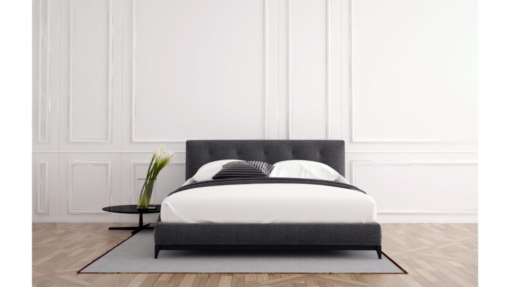 Picture of a bed with pillows  and a side table with a plant